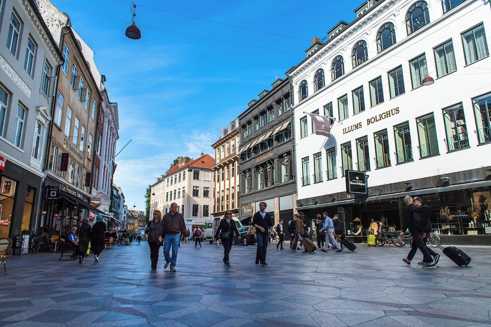 A bustling European street with historic buildings, shops, and pedestrians.