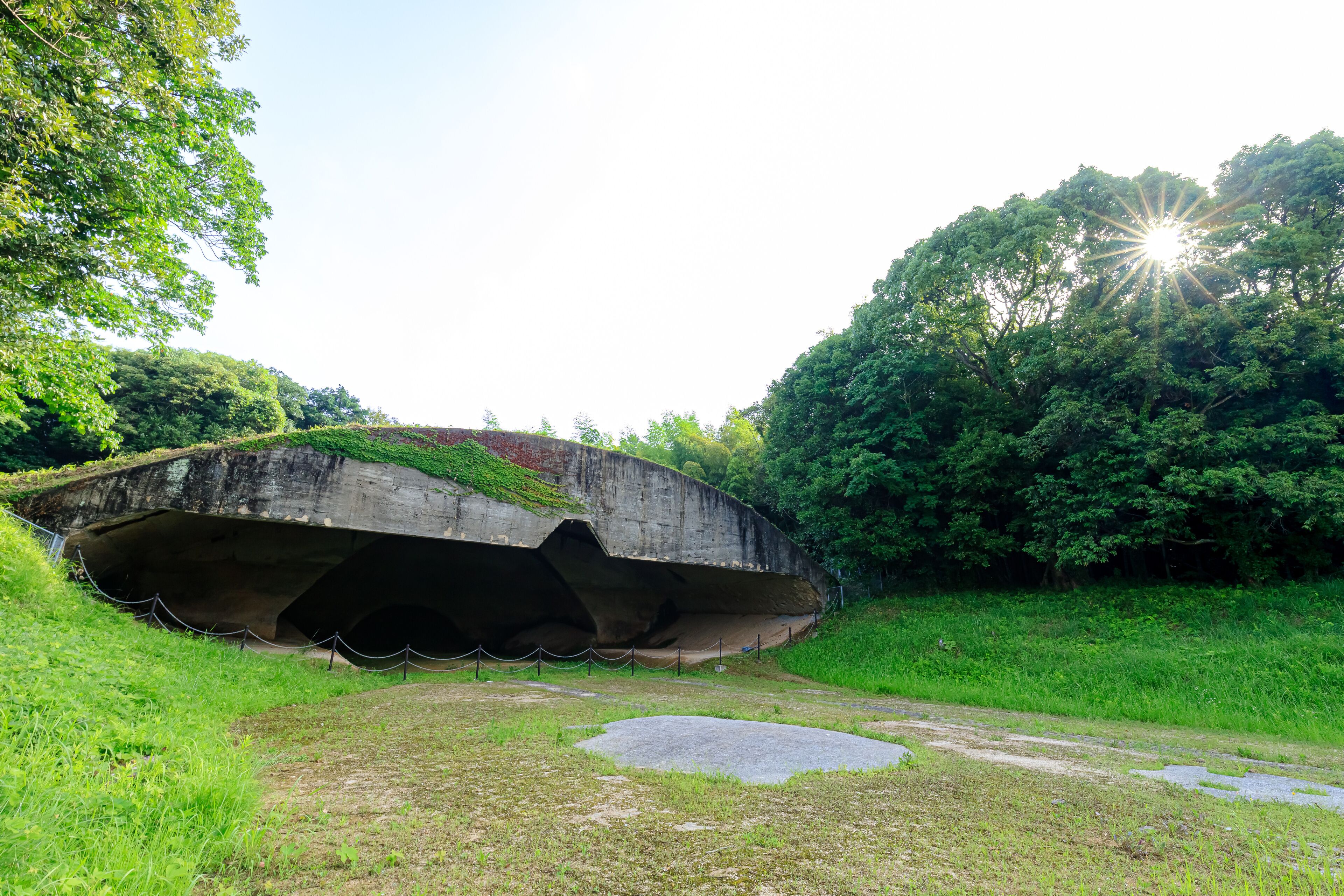 A concrete bridge over a grassy area with trees and a clear sky.