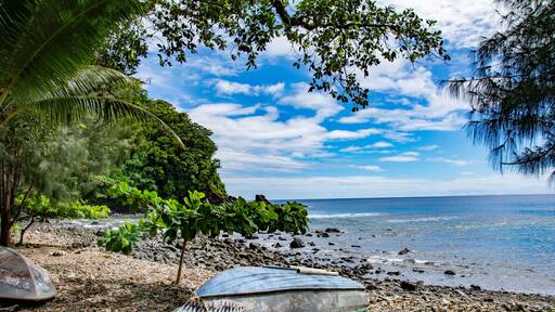 Ocean, beach, trees and small boat in Fagamalo village, American Samoa