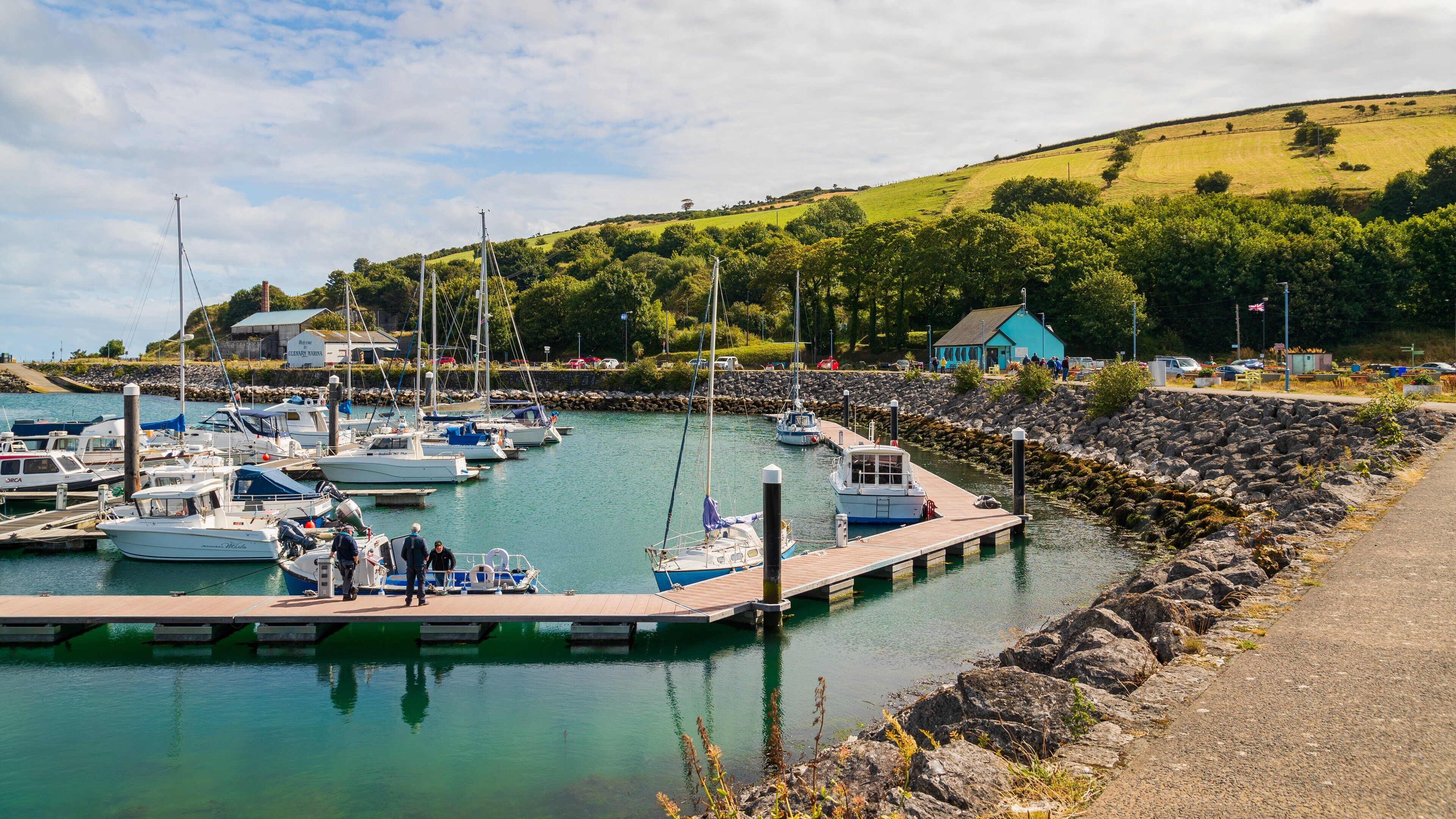 A marina with boats docked, surrounded by a rocky shoreline and greenery.