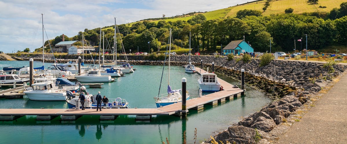 A marina with boats docked, surrounded by a rocky shoreline and greenery.
