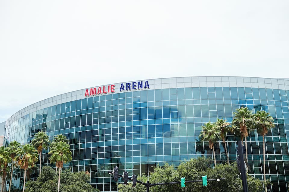 Un edificio moderno de cristal con el texto "AMALIE ARENA" en su fachada.