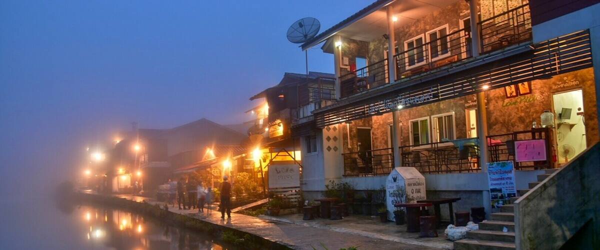 A riverside building with outdoor seating and a satellite dish.