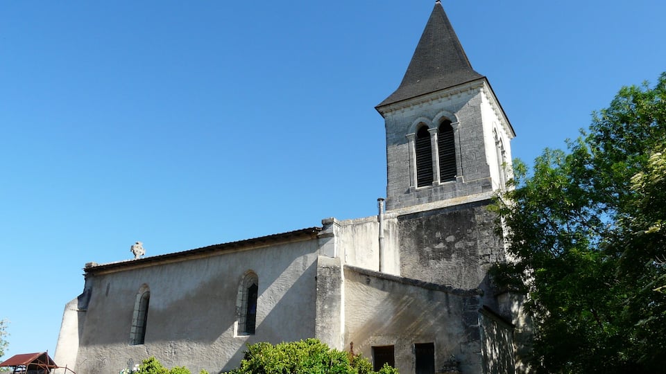 A church with a tall bell tower and a cross on top.