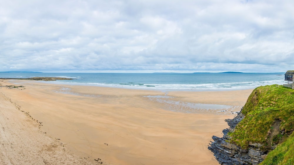Une plage de sable avec une structure en pierre sur une falaise herbeuse.