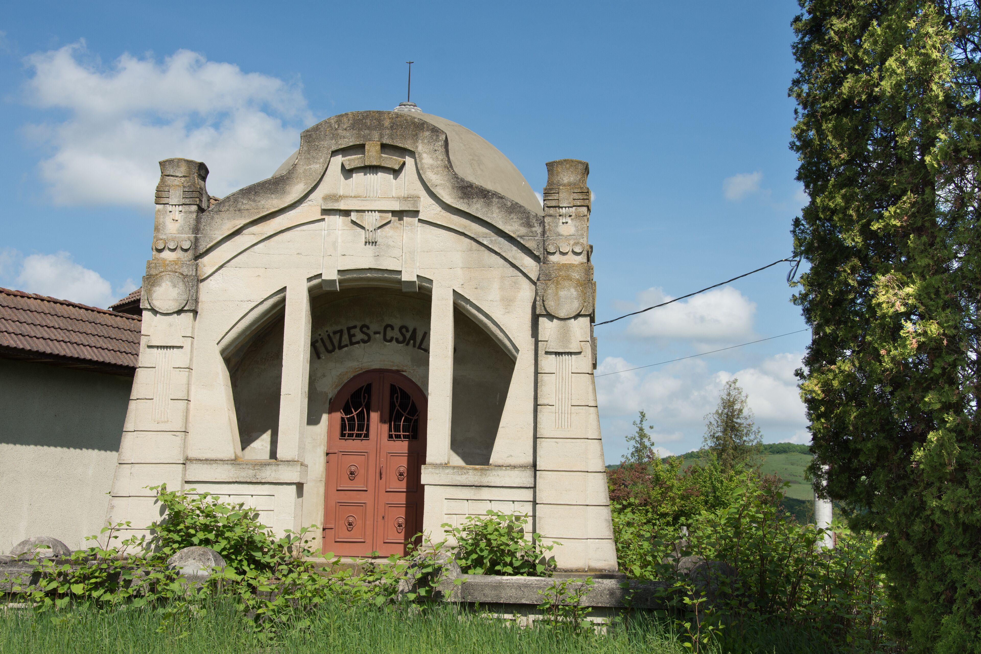 A stone building with a red door and the inscription "JUZES-CSAL" above it.