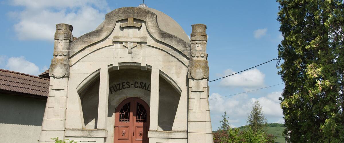 A stone building with a red door and the inscription "JUZES-CSAL" above it.