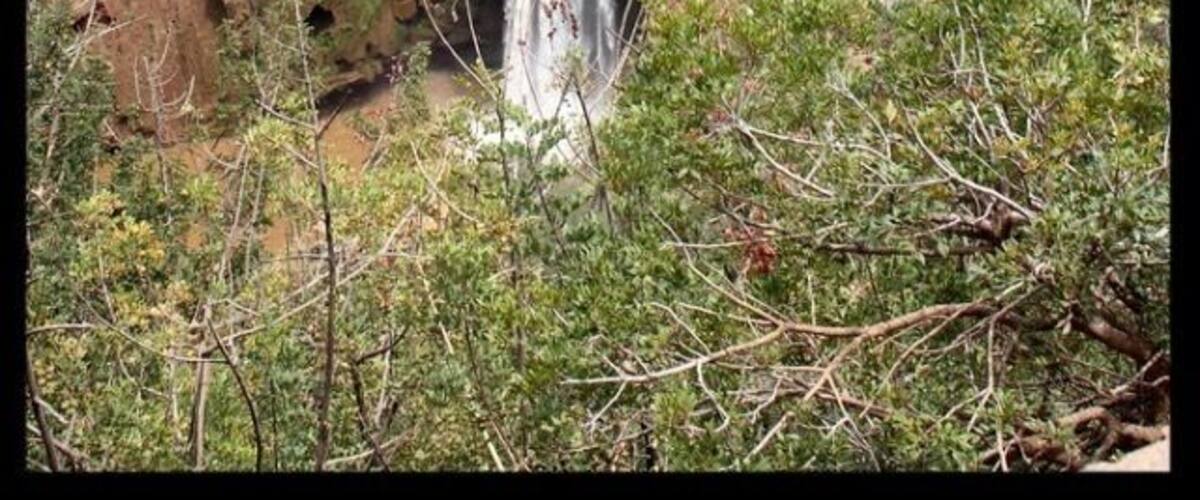 Une cascade à plusieurs niveaux, entourée d’un paysage accidenté et d’une végétation clairsemée.
