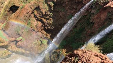 A waterfall cascading down a rocky cliff with a visible hole in the rock formation.