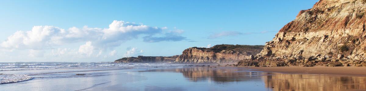Mountain reflected in the smooth water of the beach Areia Branca. Lourinha, West coast of Portugal