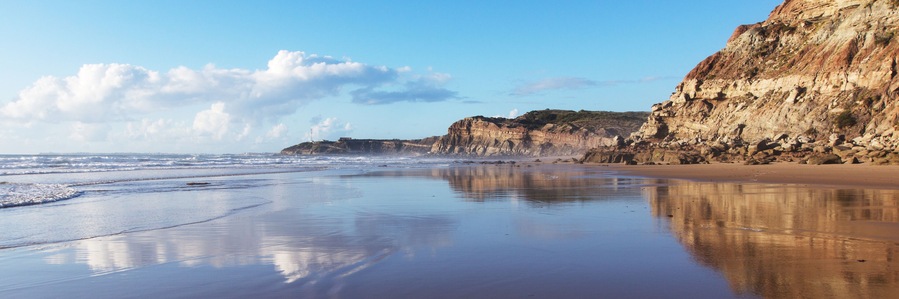 Mountain reflected in the smooth water of the beach Areia Branca. Lourinha, West coast of Portugal