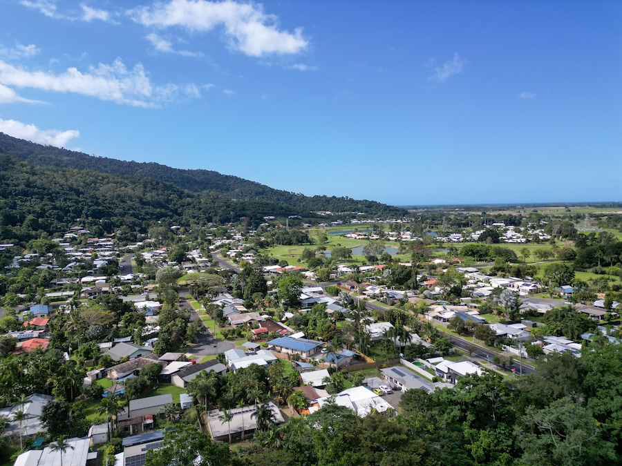 A coastal town with houses, roads, and a hilly backdrop.