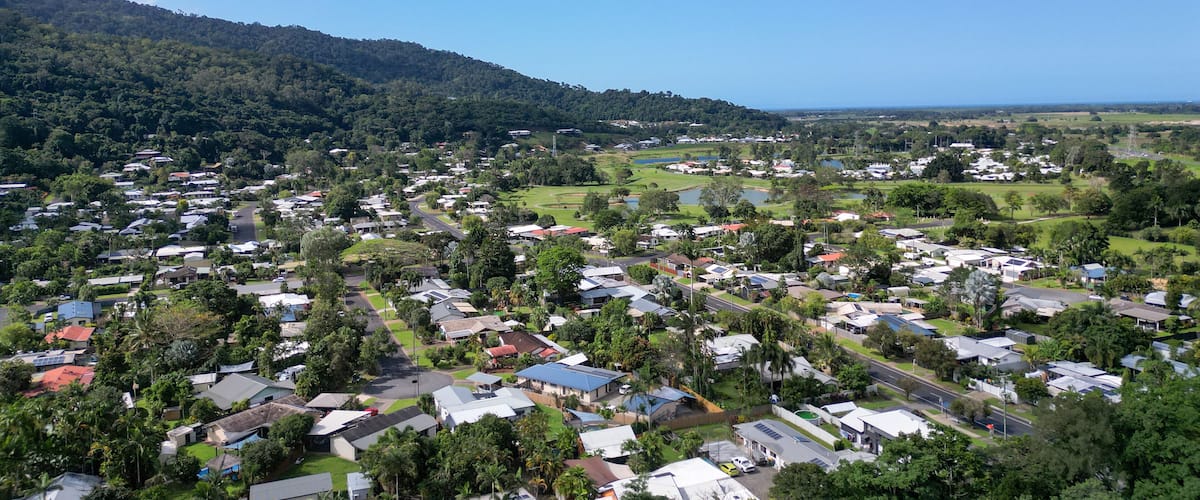 A coastal town with houses, roads, and a hilly backdrop.
