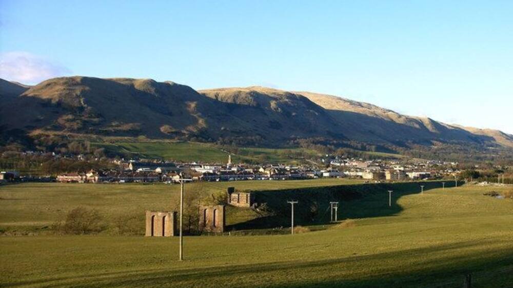 A rural landscape with a bridge, fields, and a town in the valley.