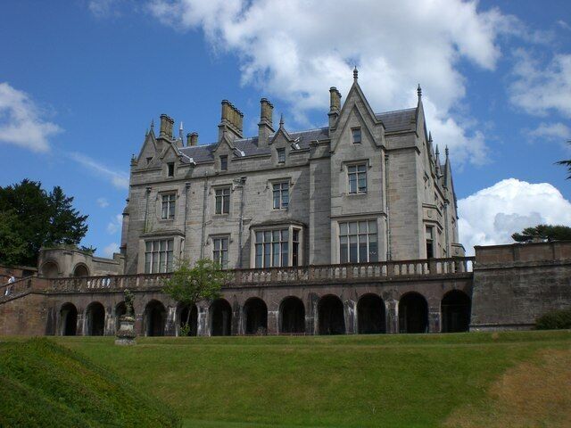 A large, historic stone building with multiple arches and a prominent tower.