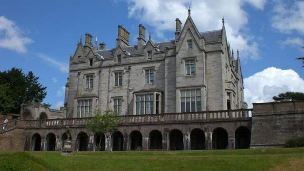 A large, historic stone building with multiple arches and a prominent tower.