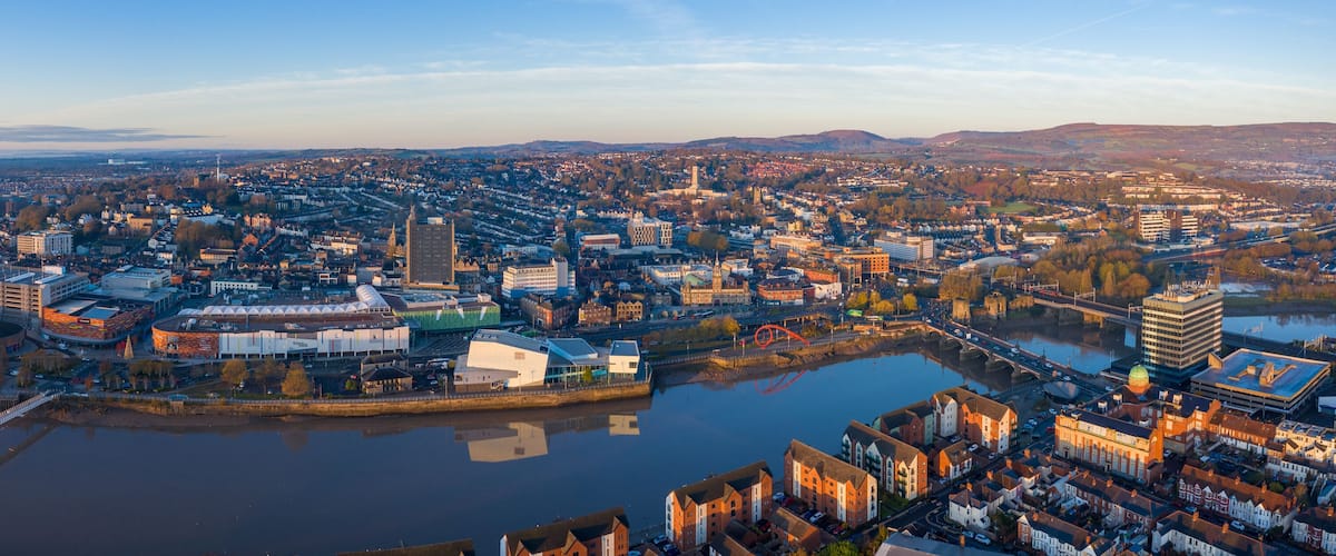 A panoramic view of a city with a river, a prominent bridge, and a mix of modern and historic architecture.