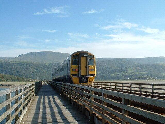 A train on a bridge with a mountainous landscape in the background.
