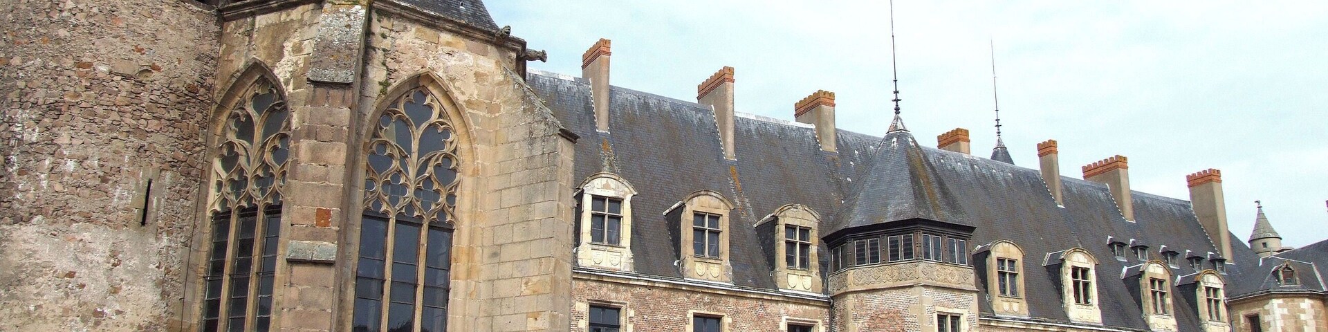 Un edificio histórico con un gran ventanal arqueado y varias chimeneas.