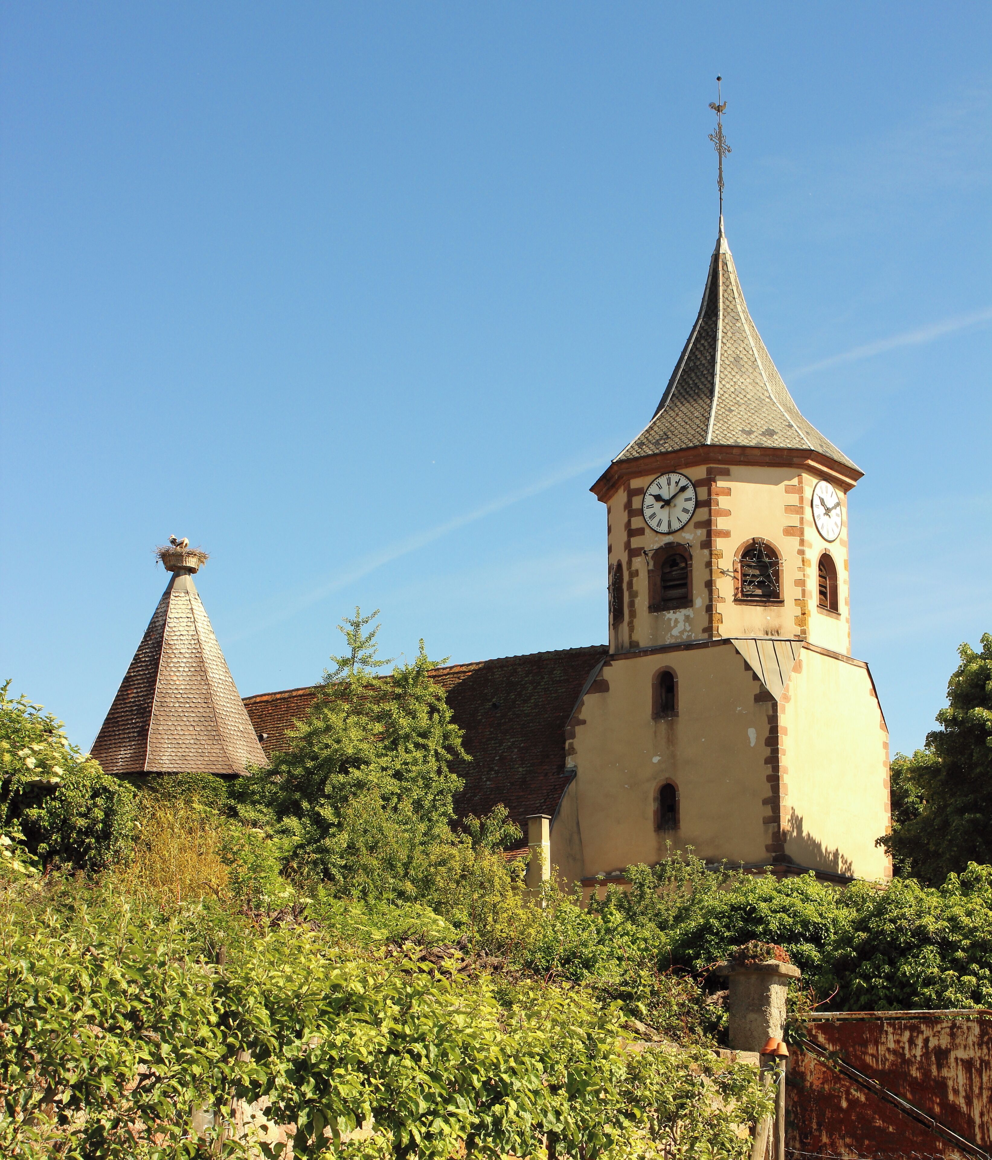 A church with a clock tower and a conical roof.