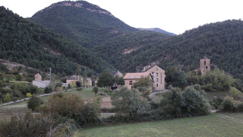 Un village rural doté d’une église et d’un clocher imposants, entouré de collines verdoyantes.