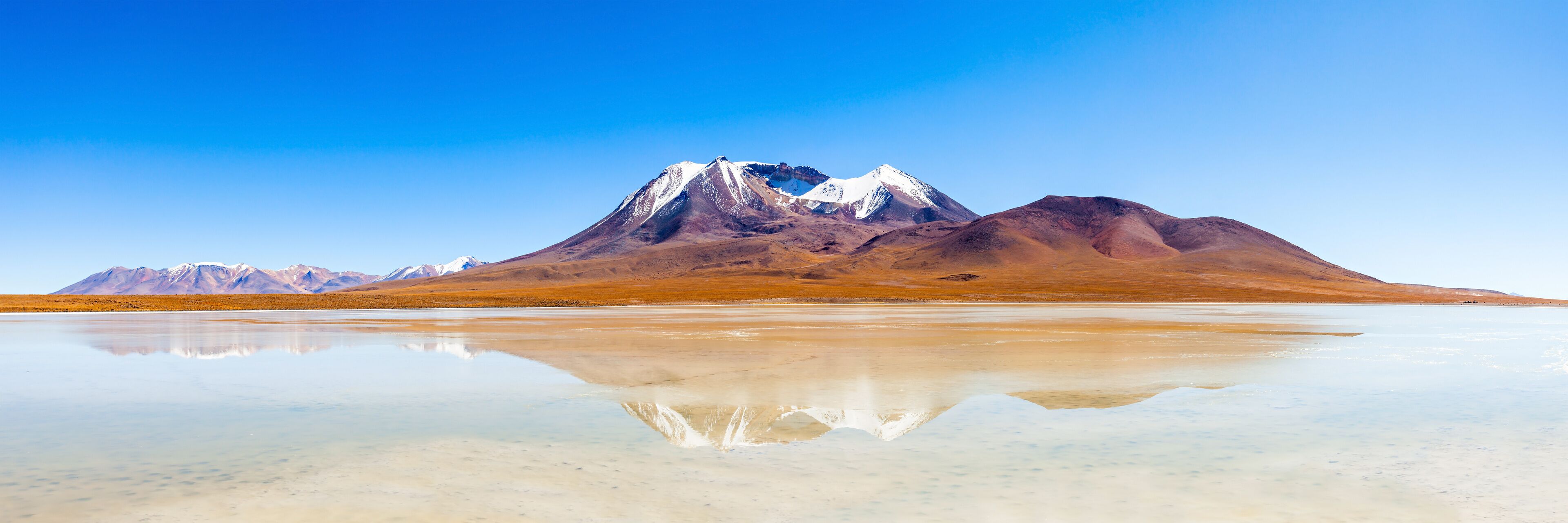 A mountain range with a reflective salt flat in the foreground.