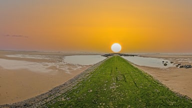 Panoramic image along a breakwater on the North Sea beach of the Belgian town Middlekerke with setting sun
