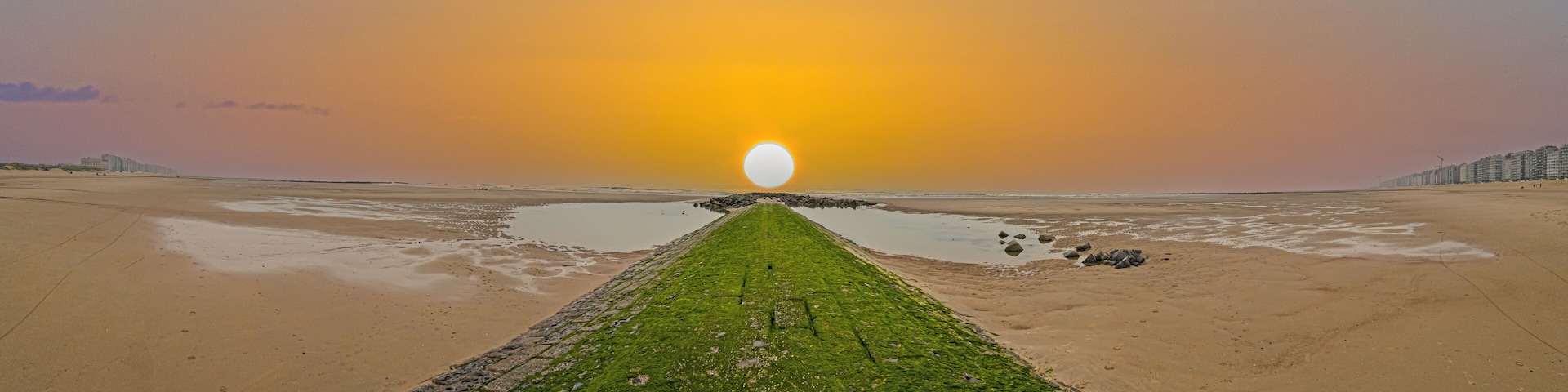 A beach with a long, narrow path leading to a large, round sun.