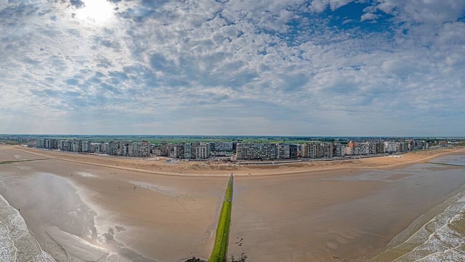 A coastal cityscape with a beach, high-rise buildings, and a clear sky.