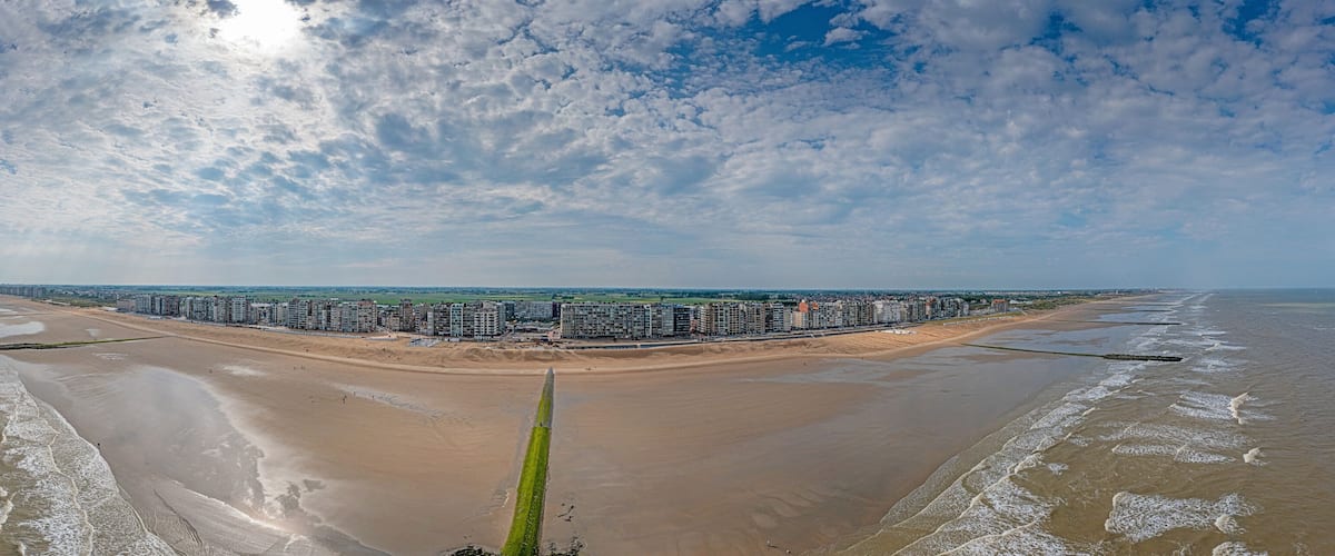 Drone panorama over the beach of the Belgian coastal town of Middelkerke at low tide with breakwaters during the day