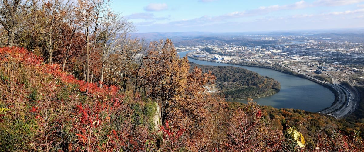 A river curving through a city, surrounded by autumn foliage.