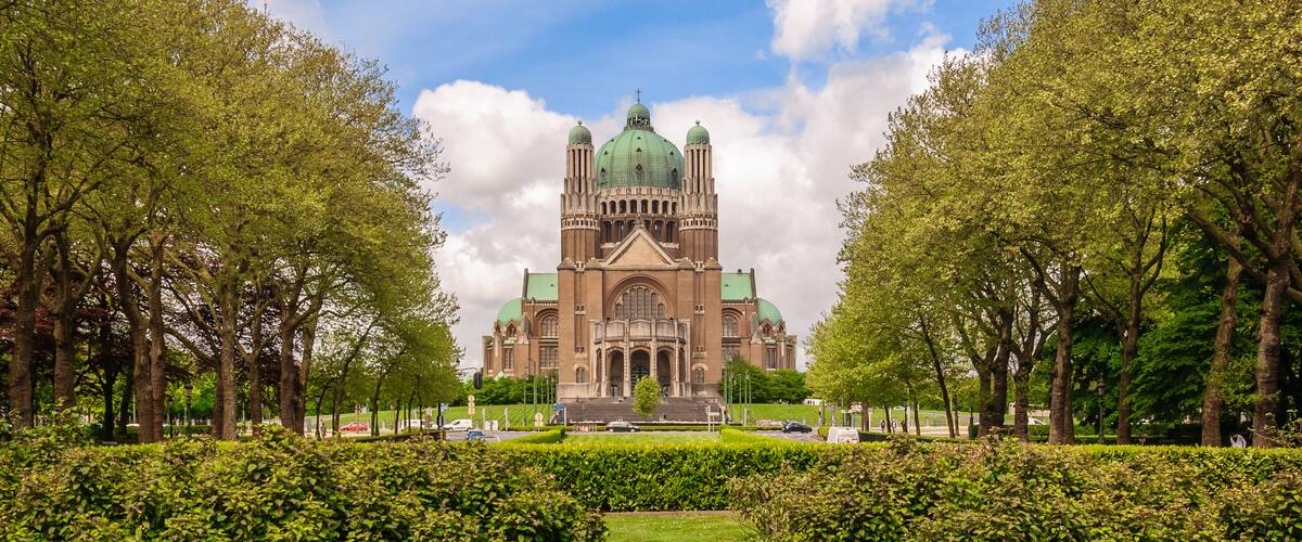A large green-domed building surrounded by well-maintained hedges and trees.