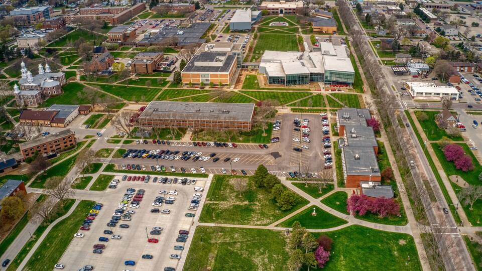 An aerial view of a campus with multiple buildings, parking lots, and green spaces.