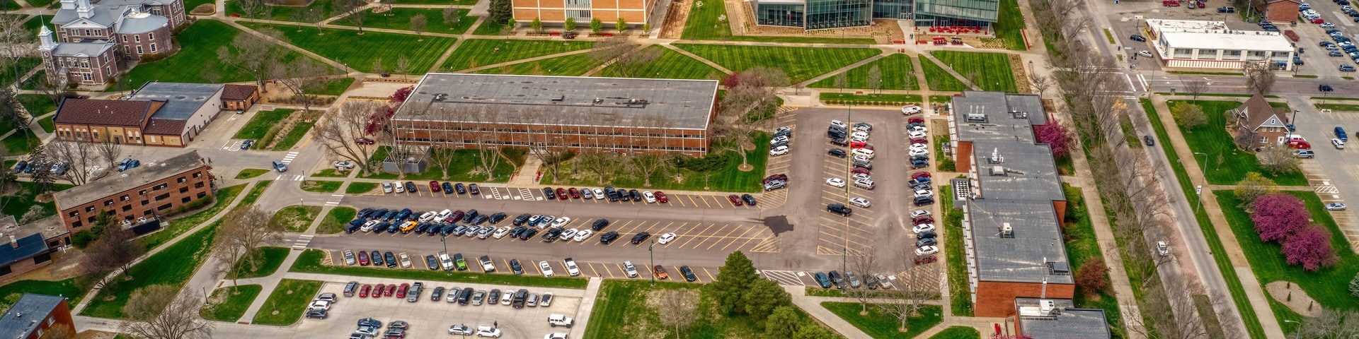 Vista aérea de um campus com vários edifícios, estacionamentos e áreas verdes.