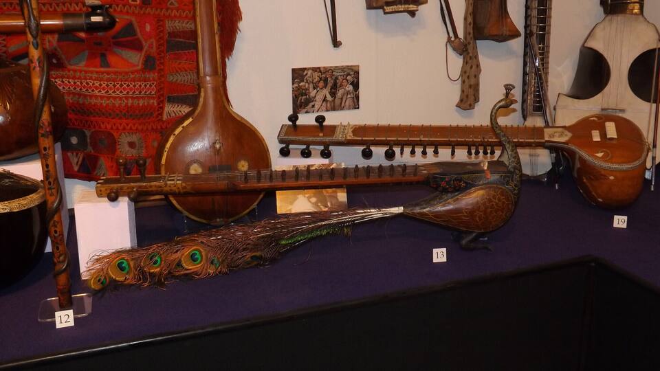 A collection of stringed musical instruments, including a lute, a guitar, and a violin, displayed on a purple surface.