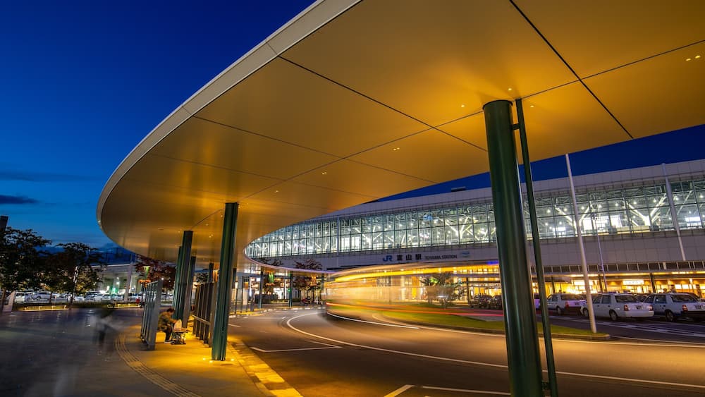 A modern train station with a curved roof and glass facade.
