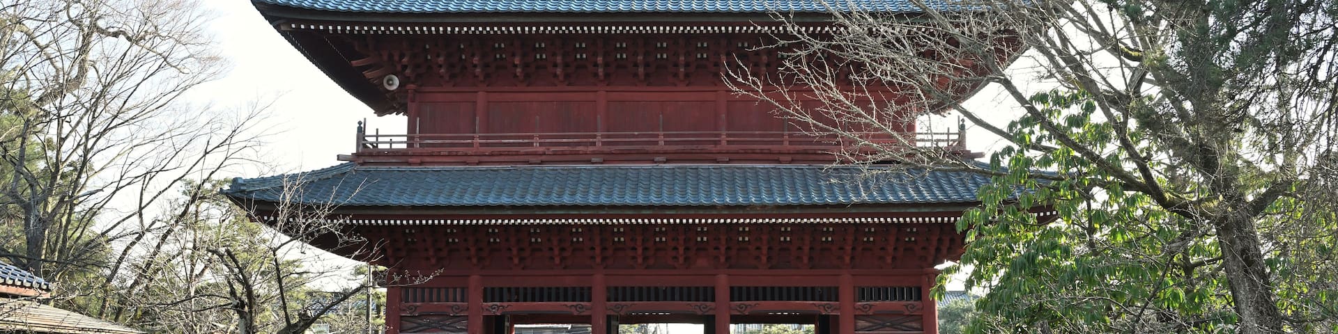 A traditional Japanese building with a tiled roof and red walls.