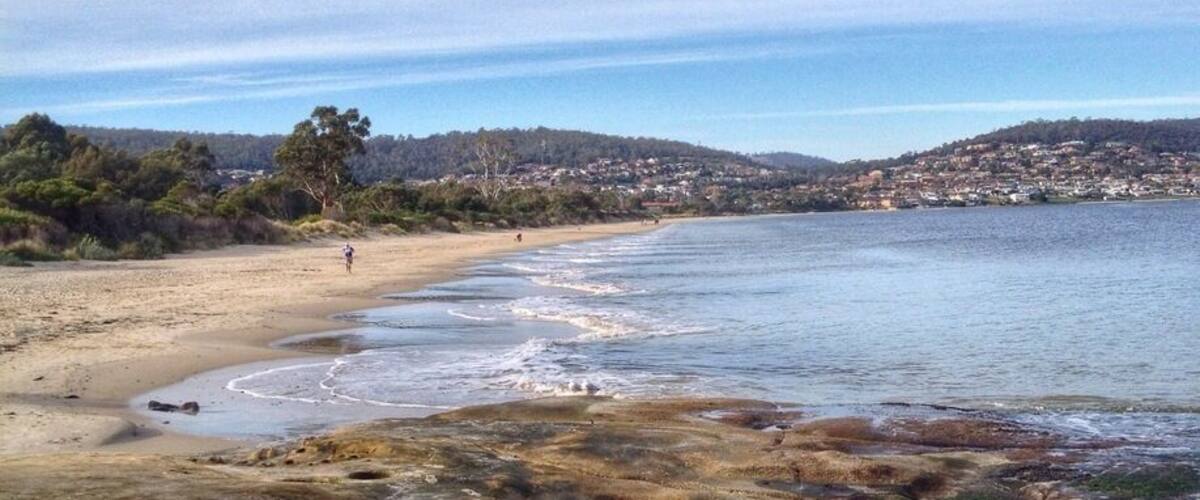 Nice beaches close to the city centre are hard to find - most are tiny or don't have much sand to enjoy. Howrah is about a 10-minute drive from Hobart city and you can bring the pooch. 
You'll get a lovely view of the city, river and Mount Wellington.