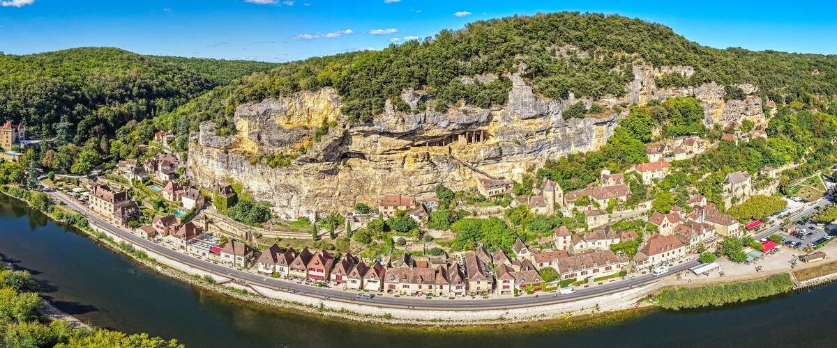 A river winding through a town with historic buildings and a cliffside.