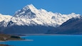 A snow-capped mountain range with a turquoise lake in the foreground.