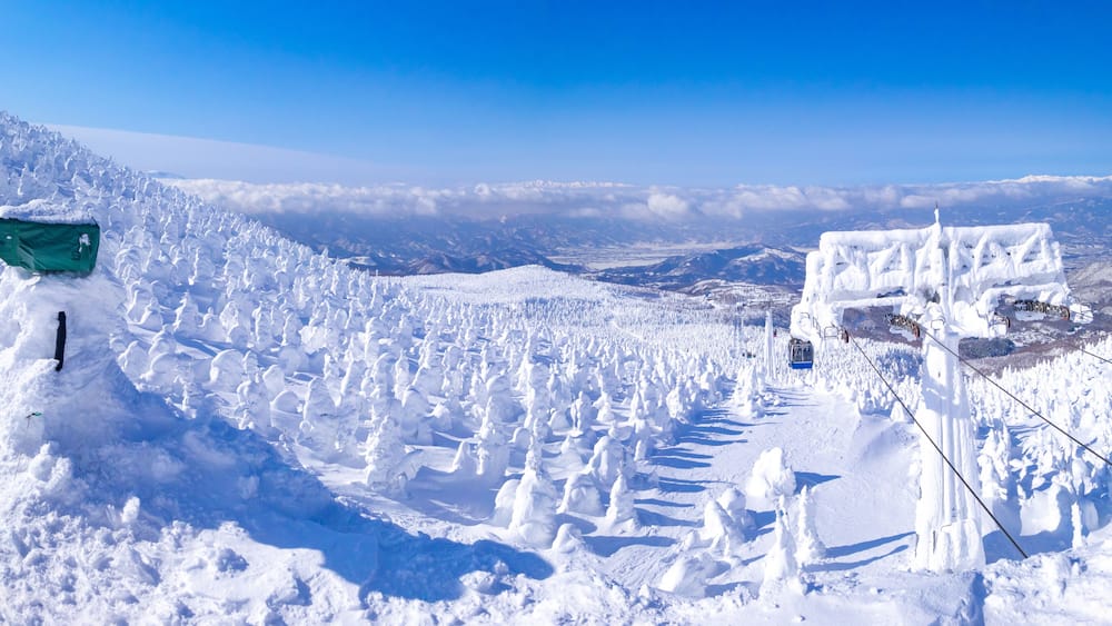 A snow-covered mountain landscape with a ski lift and a green sign.