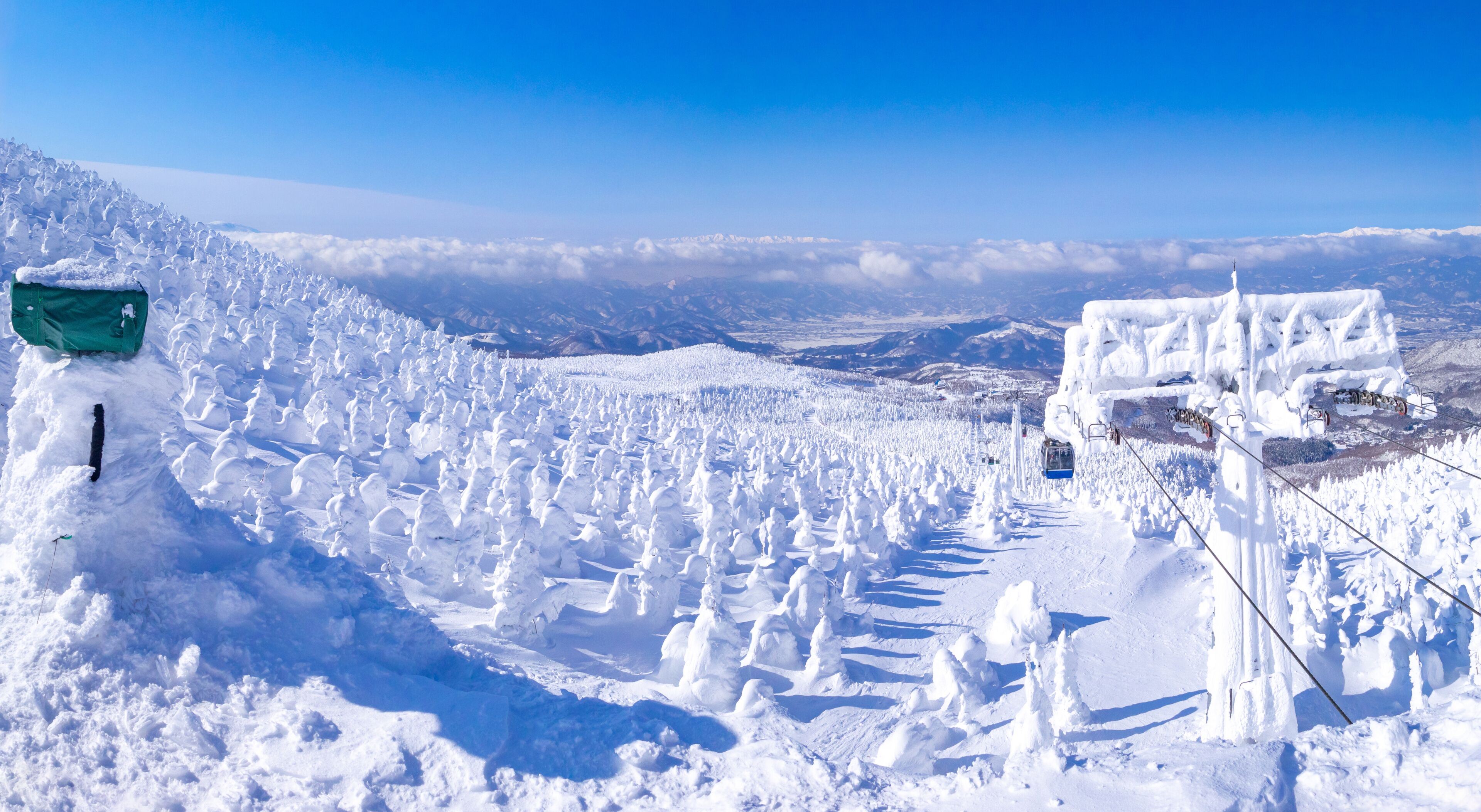 A snow-covered mountain landscape with a ski lift and a green sign.