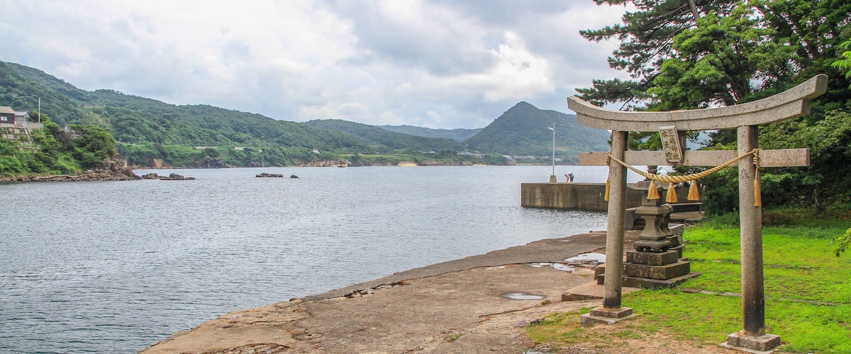 A calm river with a traditional stone bridge and a mountain backdrop.