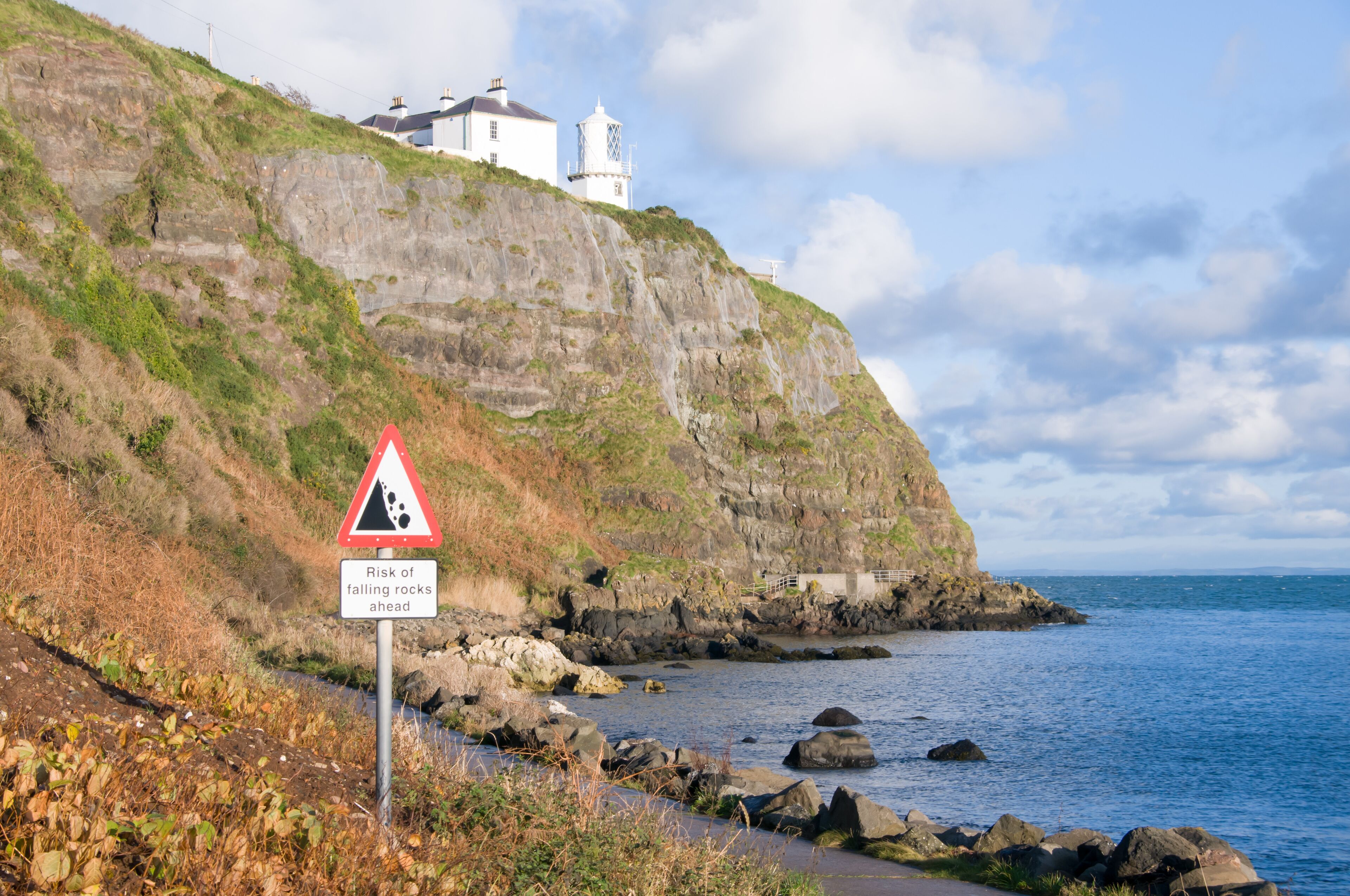 Whitehead/Blackhead lighthouse on cliffs above Belfast Lough.  Danger Falling Rocks sign.