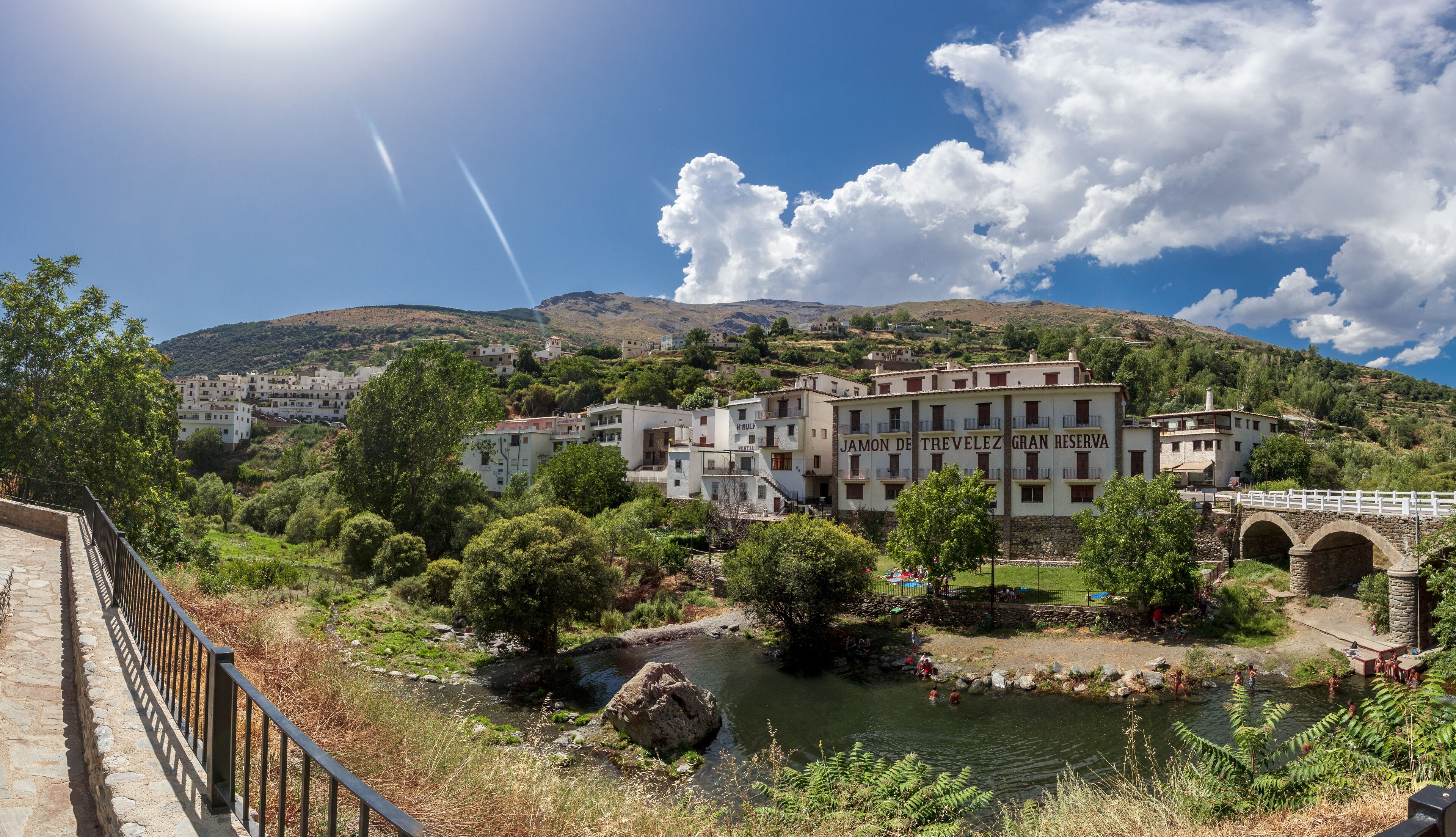 A mountainous landscape with a river, a bridge, and a building labeled "Jamon de Trevelez Gran Reserva".