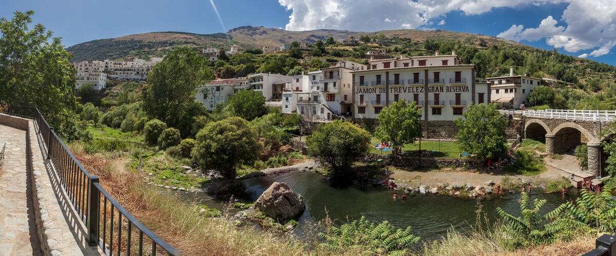 A mountainous landscape with a river, a bridge, and a building labeled "Jamon de Trevelez Gran Reserva".