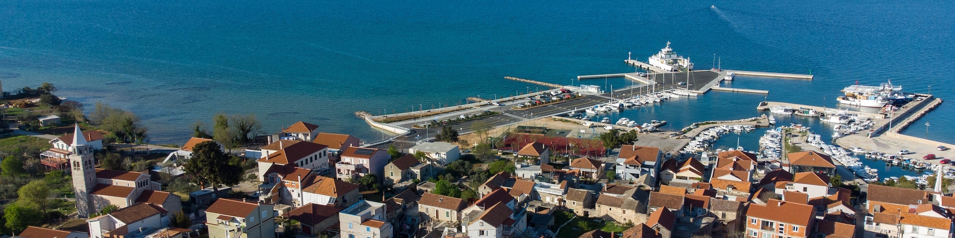 A coastal town with a marina, boats, and a church.