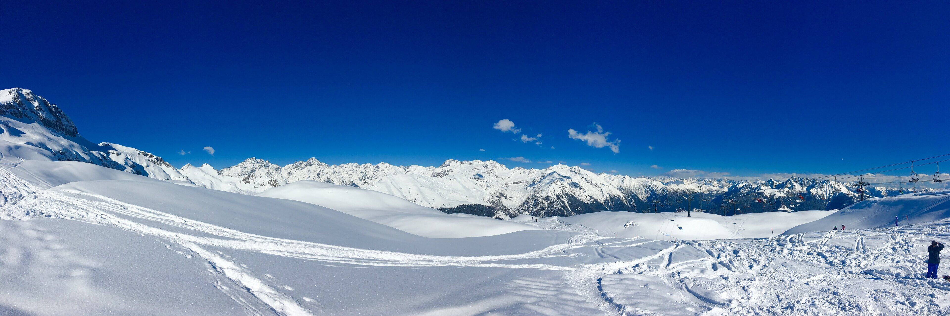 A snowy mountain landscape with ski slopes and a clear blue sky.
