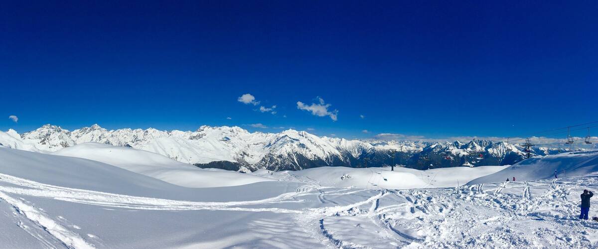 A snowy mountain landscape with ski slopes and a clear blue sky.