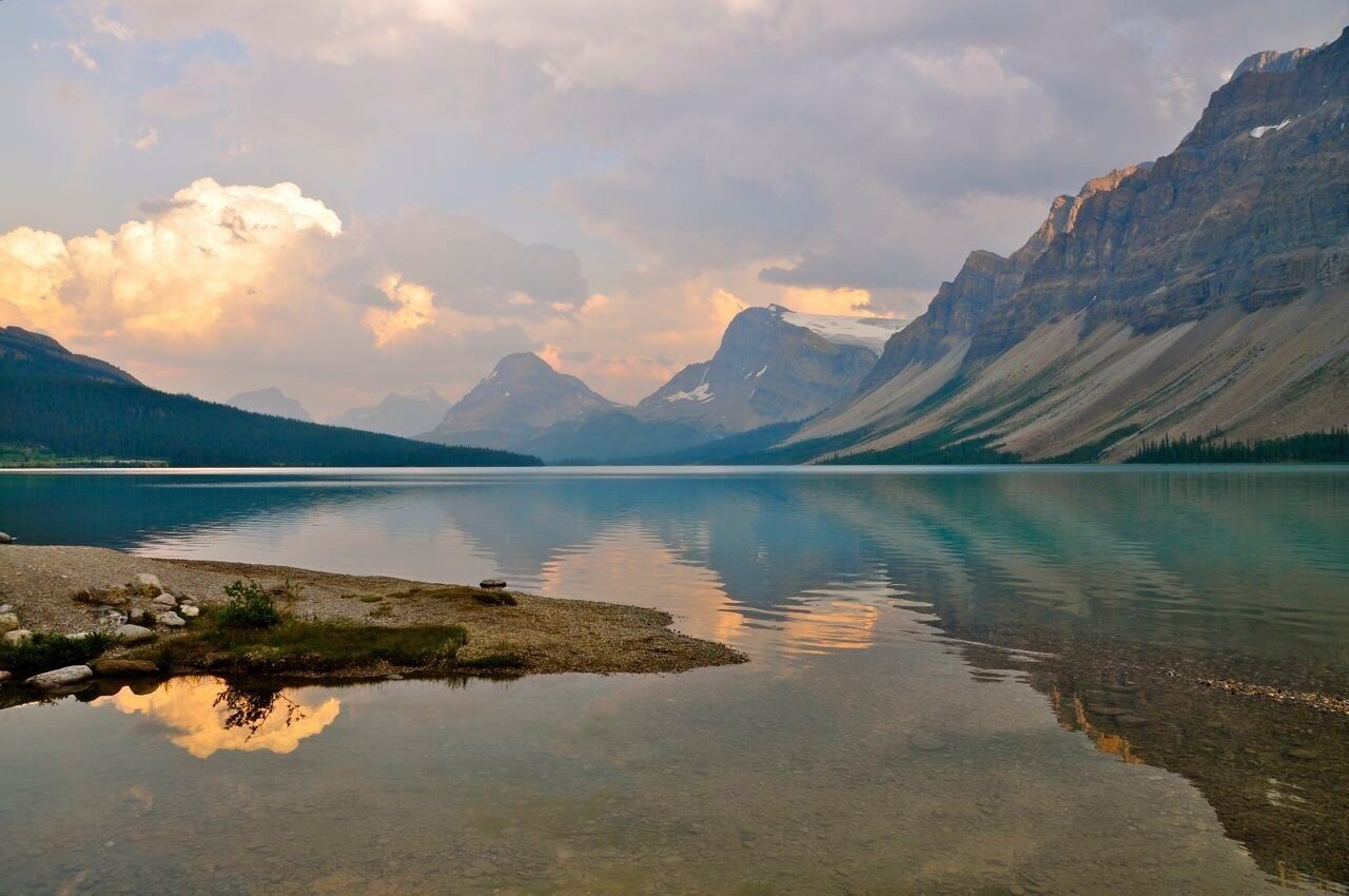 A calm lake surrounded by mountains with a clear sky.
